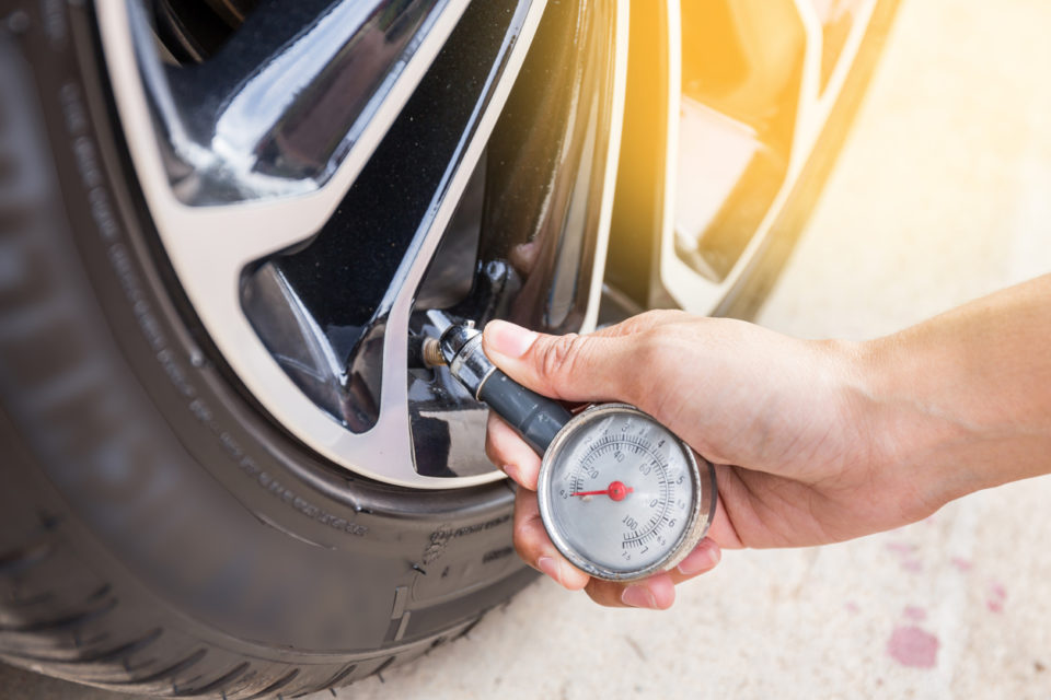 Close-Up Of Hand holding pressure gauge to check tire pressure