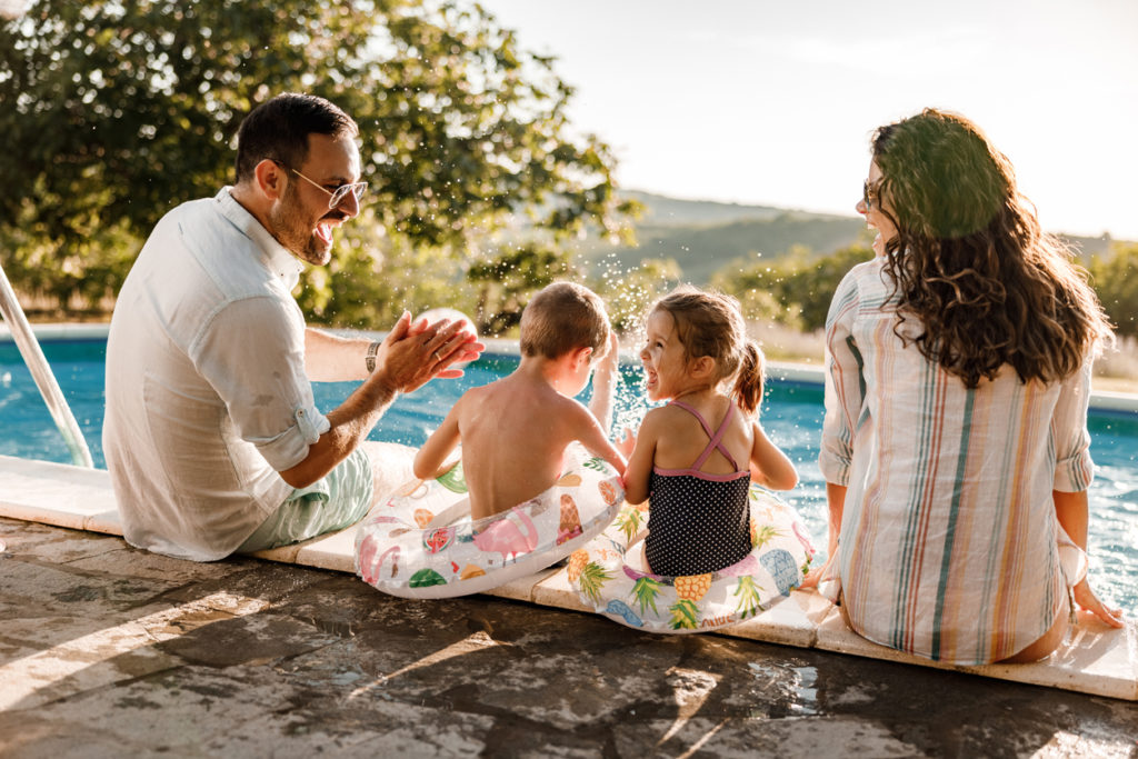 Happy family talking by the pool in summer day.