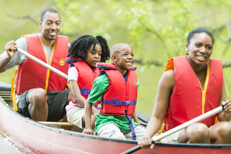 Happy family on summer vacation together canoeing on a lake.