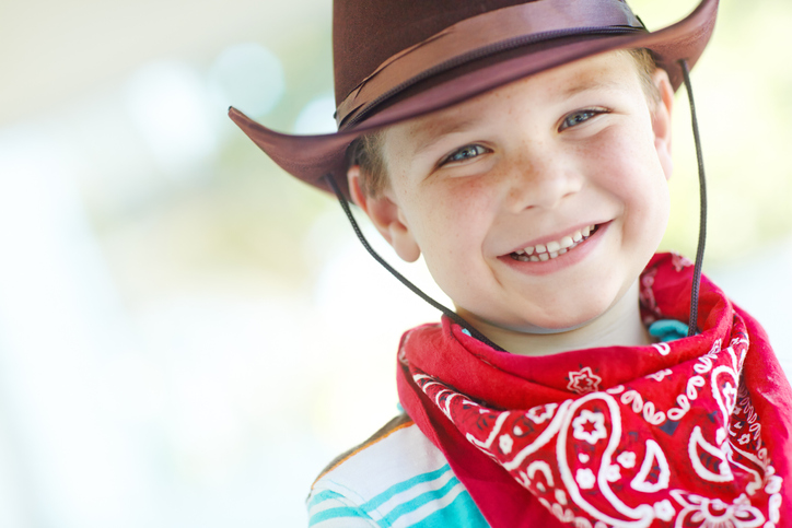 A cute little boy dressed in cowboy-themed attire while at home