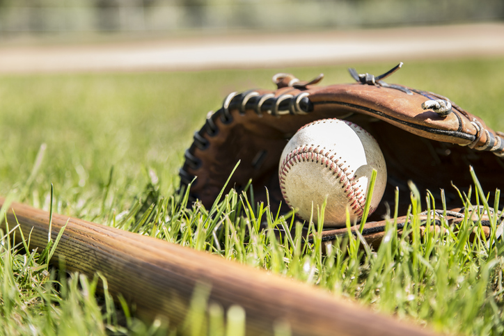 Spring and summer baseball season is here.  Wooden bat, glove, and weathered ball lying on baseball field in late afternoon sun.  No people.  Great background image.
